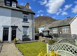 a house with a bench in front of a yard at Ruby's Cottage in Threlkeld