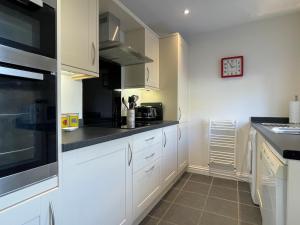 a kitchen with white cabinets and black counter tops at Ruby's Cottage in Threlkeld