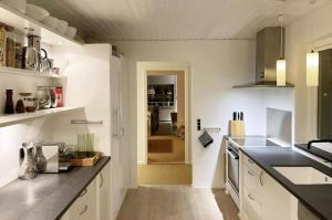 a kitchen with white cabinets and a black counter top at Skagen Beach House in Ålbæk