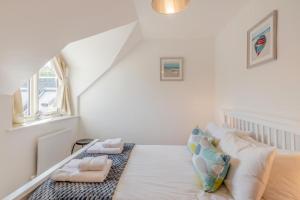 a white bedroom with a bed with pillows and a window at 3 Bed in Chathill oc-61892 in Beadnell