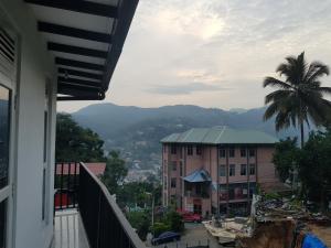 a balcony with a view of a building and a palm tree at Shalom View Homestay in Kandy