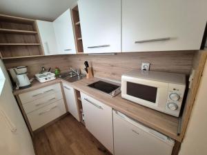 a small kitchen with white cabinets and a microwave at Apartments Makin by El-Pi Tours in Njivice