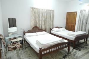 a bedroom with two beds and a chair and a mirror at Pulimada Stays in Trichūr