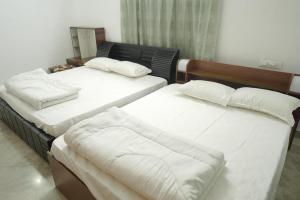 two beds in a room with white sheets and pillows at Pulimada Stays in Trichūr +4 photos
