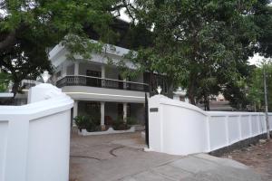 a white fence in front of a white house at Pulimada Stays in Trichūr