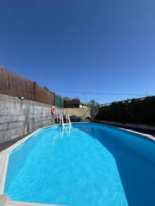a blue swimming pool with two chairs in it at Casa do terno com piscina in Arco da Calheta