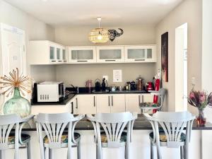 a kitchen with white cabinets and a table and chairs at Adrift Guesthouse in St Francis Bay