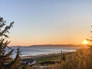 a sunset on a beach with the sun setting over the ocean at Dunrigh Cottage in Blackwaterfoot