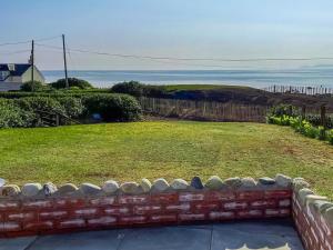 a yard with a brick retaining wall and a lawn at Dunrigh Cottage in Blackwaterfoot +12 photos