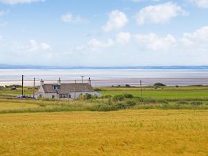 a house in a field next to the ocean at Arthurs Cottage - Uk51636 in Kirkbean