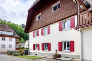a white building with red shutters on it at Haus Belchenwind in Münstertal