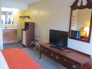 een slaapkamer met een televisie op een dressoir met een spiegel bij Astro Best Inn in Houston