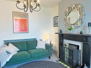 a living room with a green couch and a mirror at Irisdene in Tintagel