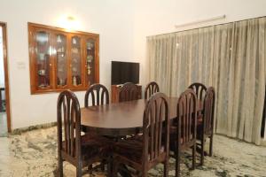 a dining room with a wooden table and chairs at Pulimada Stays in Trichūr