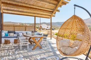 a swing on a patio with a table and chairs at Revery Villa & House in Ios Chora