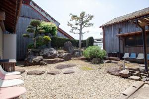 a garden with chairs and rocks in front of a building at Guest House Maru in Kashima