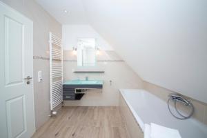 a white bathroom with a sink and a blue sink at Schleitraum Appartement in Rabenkirchen-Faulück