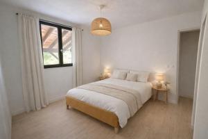 a white bedroom with a bed and a window at Les cabanes in Noaillan