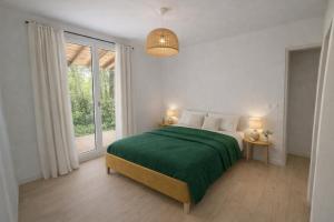 a white bedroom with a green bed and a window at Les cabanes in Noaillan