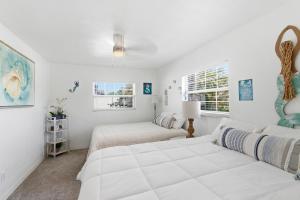 two beds in a room with white walls and windows at Spacious 4 bedroom 3 bath Clearwater Vacation House Cowboy Pool Fire Pit Games Close to Clearwater Beach Biking Trail Farmers Markets Harbor Health Spa Baycare Ballpark and Ruth Eckerd Hall Golf Courses in Clearwater +69 photos