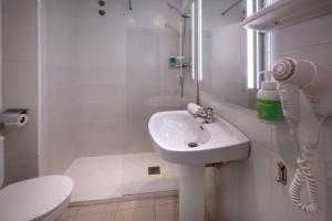 a white bathroom with a sink and a shower at Hotel GHT Simeon in Tossa de Mar