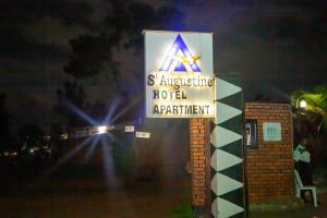 a sign for a hotel at night at St Augustine Apart & Hotel in Kigali
