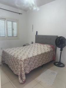 a bedroom with a bed with a blanket and a fan at Germinada in Imbé