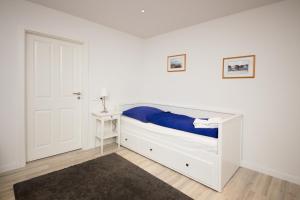 a bedroom with a white bed with a blue blanket at Schleiblick Familienappartement 13 in Rabenkirchen-Faulück