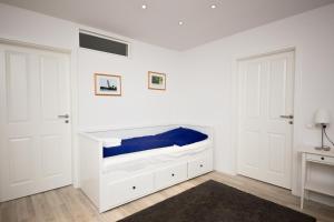 a white bedroom with a bed with blue sheets at Schleiblick Familienappartement 13 in Rabenkirchen-Faulück