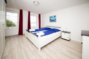 a bedroom with a white bed and red curtains at Schleiblick Familienappartement 13 in Rabenkirchen-Faulück