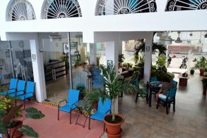 un restaurante con sillas azules, mesas y plantas en Hotel Jungle House, en Iquitos