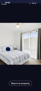 a white bedroom with a bed and a window at La Barca in Rye +2 photos