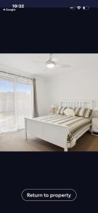 a white bed in a room with a window at La Barca in Rye