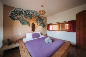 a bedroom with a bed with a tree mural on the wall at Vida Pura Apartments in Odeceixe