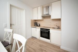 a kitchen with white cabinets and a sink and a stove at Schleiblick App 19 in Rabenkirchen-Faulück