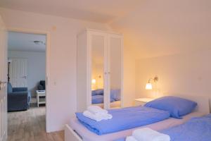 a bedroom with two beds with blue sheets and a mirror at Schleiblick App 19 in Rabenkirchen-Faulück