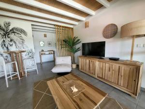 a living room with a flat screen tv and a table at Évasion Tropicale - vue et plage à 2 min in Les Trois-Îlets