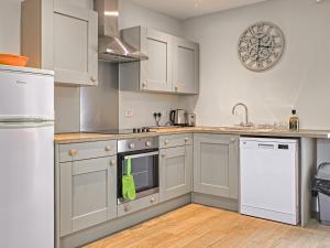 a kitchen with gray cabinets and white appliances at Beachcmbers Cottage - Uk51638 in Carsethorn