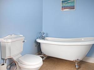 a bathroom with a white tub and a toilet at Beachcmbers Cottage - Uk51638 in Carsethorn +10 photos