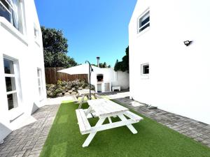 a patio with two picnic tables and an umbrella at Adrift Guesthouse in St Francis Bay