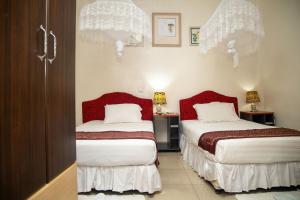 a bedroom with two beds with red and white sheets at St Augustine Apart & Hotel in Kigali