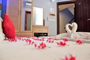 twee zwanen en bloemen op een bed in een kamer bij Elite Beach Inn in Hulhumale
