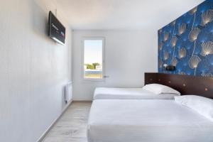 a hotel room with two beds and a tv at Fasthotel Angers Beaucouzé in Beaucouzé +6 photos