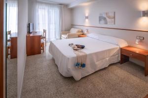 a hotel room with a bed with a teddy bear on it at Hotel GHT Simeon in Tossa de Mar