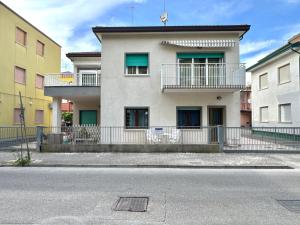 a white building with green windows on a street at Appartamenti Mare Caorle in Caorle