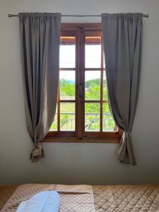 a window with curtains and a bed in a room at Beautiful apartment with mountain view in Paralio Astros