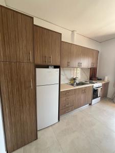 a kitchen with a white refrigerator and wooden cabinets at Beautiful apartment with mountain view in Paralio Astros +10 photos