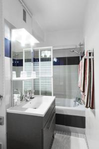 a white bathroom with a sink and a tub at Le Studio 1517 in Le Kremlin-Bicêtre