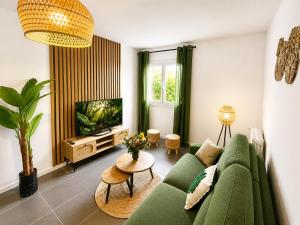 a living room with a green couch and a tv at " Souffle Vert " Wifi - TV - 4 personnes in Muret