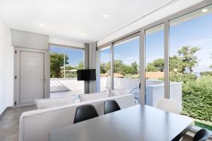 a living room with white furniture and large windows at SunBlue Boutique Villas in Skala Rachoniou
